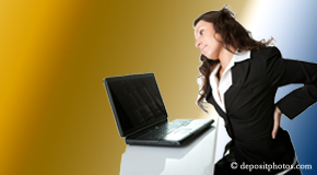 a person Groton bending over a computer holding her back due to pain